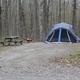 Tent campsite in a forested setting with picnic table and cleared pad — shows primitive/tent camping option offered at the property (from waystostay photos on the campground page).