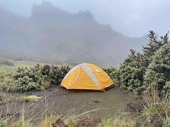 orange tent in dirt patch with foggy cliff