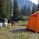 A bright orange tent and a family picnicking at Slough Creek
