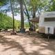 Clear campsite view showing an RV parked on a gravel pitch with chairs and firepit, trees, and the Saco River in the background — matches the property’s riverside sites; this file is used as the site’s social/hero image on the homepage.