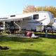 Photo of a fifth-wheel setup on a maintained grassy site with picnic table and patio — another representative RV site view showing site layout and landscaping.