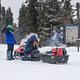 Two snowmobilers wait next to an information kiosk.