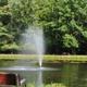 Pond with central fountain and bench — shows a distinctive on-site water feature and landscaped shoreline seen on the campground homepage background image, supporting this is on the property.