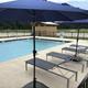 Pool deck with lounge chairs and umbrellas overlooking the fenced pool area — clear image of the resort’s swimming facility and outdoor amenities.