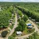 High, wide aerial view showing campground layout with multiple RV sites, roads and surrounding woods — clear property overview consistent with site hero/background images on the property homepage.