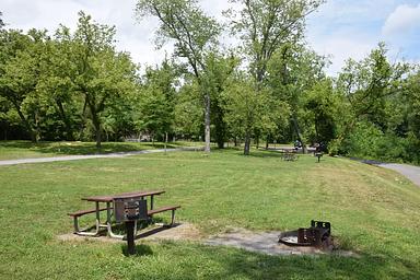 Single Campsite with a picnic table, fire ring and grill in the foreground.