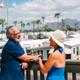 A man and woman smiling and chatting on a deck overlooking palm trees and a community of white homes with mountains in the background in apache junction az