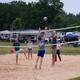 Sand volleyball court with RVs and campsites visible in the background — shows recreational facilities and adjacent camping spaces on-site (used on site background content).