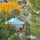 Elevated/landscape view showing a yurt nestled among trees with fall color — useful aerial/setting photo demonstrating the property’s natural surroundings; sourced from the site’s yurt/gallery content.