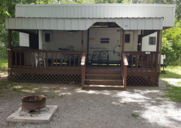 Exterior view of a rental camper with covered porch/deck — demonstrates on-site rental accommodations; from the Rental Campers page.