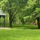 Grassy, tree-filled area with playground equipment visible — shows recreational area and setting on the property (from Campground Rentals page).