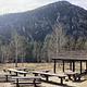 Picnic area with pavilion, wooden picnic tables with mountains and trees in the background