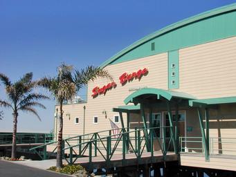 Front exterior of the Sugar Barge building with entrance ramp and signage — shows the waterfront bar & grill facility on the property (used as site header image).