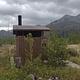 Outhouse on cloudy day with mountain in background