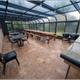 Interior photo of an enclosed solarium/covered picnic area with tables and grills — shows on-site guest facilities (Activities page).