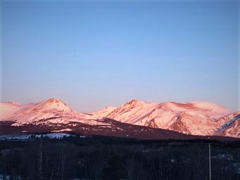 Distant mountains lit by sunrise/sunset — photographic exterior view used on the lodging page that highlights the surrounding mountain scenery visible from the property.