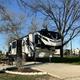 Close-up of a single RV on a concrete pad with picnic table and landscaped edging — good detailed view of an individual RV site and site furnishings (from the home page imagery).