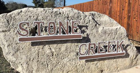 Stone entrance rock sign with the park name clearly visible — identifies the property entrance and provides a recognizable landmark for guests.