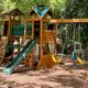 Children’s wooden playground structure set among trees—demonstrates family-friendly on-site recreation shown on the park homepage.