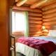 Interior bedroom in a log-cabin room — useful for illustrating cabin accommodations and interior character of the lodge.