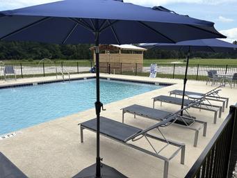Pool deck with lounge chairs and umbrellas overlooking the fenced pool area — clear image of the resort’s swimming facility and outdoor amenities.