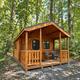 Rustic single cabin in a wooded setting with a front porch and seating — useful to show variety of cabin accommodations and woodland setting.