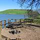 Campsite within Buckhorn Campground showing picnic table, firepit, and lake in background.