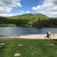 Lakeside beach view with grassy area, small play structure and surrounding hills — useful scenic view of the campground’s beach and waterfront recreation area from the property page.