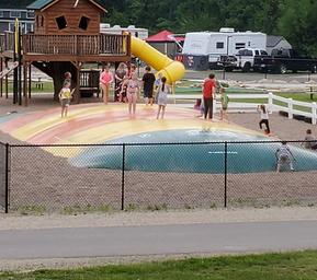 Large bounce pad/park area with playground and RVs in background — good view of activity area and adjacent RV sites (from Amenities page).