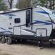 Parked travel trailer at a forested campsite with picnic setup — represents RV sites and campsite character. Shown on the site’s home page gallery (Slide-AlphaWolf) for the campground.
