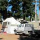 Clear photograph of RVs, tent and campsite area with picnic table and mature trees — directly shows on-site camping facilities. From the Park Rates page (https://www.rervpark.com/rates).