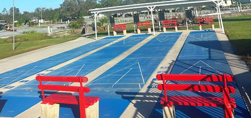 Outdoor courts (shuffleboard or similar) with seating and covered benches — depicts on‑site recreational facilities. Image appears on the homepage and matches other site amenity photos.