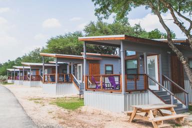 Row of exterior tiny cabins along a paved path — clear overview of cabin accommodations and layout, from the property's gallery page.