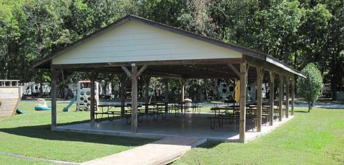 Covered pavilion with picnic tables and adjacent playground area — corresponds to the site’s facilities description (pavilion, bathhouses, and central gathering area).