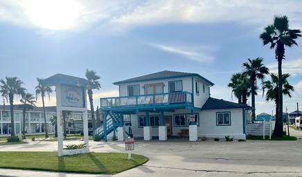 Front/entrance view of the office/building and sign with palms and property grounds visible — useful for identifying the resort entrance and office location (from homepage background).