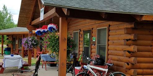 Front porch of a log/cedar cabin with outdoor seating and bikes — clear view of guest lodging and amenities (file from the site showing decorated cedar cabin).