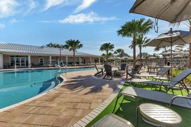 Clear ground-level photo of the resort-style pool, surrounding deck chairs and clubhouse in background—matches homepage/gallery pool images and highlights the main amenity area.