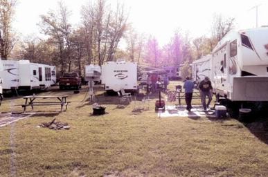 Well-framed view of multiple RVs and picnic areas among trees showing typical wooded/shady RV sites; comes from the campground’s photo gallery (Whitetail Ridge Campground Photos).