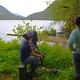 Three people looking at the view of lake with greenery around