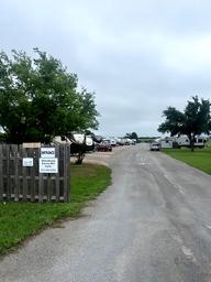 Driveway/entrance view with fencing, sign and lined RVs visible — useful for showing access and typical site layout; sourced from the Park Information page.