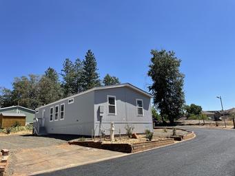 Exterior shot of a mobile home with surrounding road/landscape — shows placement and street layout within the park (matches listings on the property page).