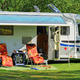 Photo of an RV at a campsite with awning and outdoor chairs; from the site's 'RV' ways-to-stay section — shows typical RV pitch and site setting.