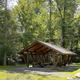 A brown picnic shelter with green trees in the background
