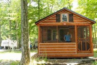 Front view of a park-model cabin on a wooded site — clearly depicts on-site cabin rental accommodation. Image appears on the Park Model Cabin Rental page of the property website.
