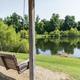 Covered swing overlooking a pond/reflective lake with tree-lined shore — good scenic shot of the campground’s lake and relaxation area (homepage gallery background).