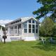 Large clear photo of a waterfront cottage/unit on manicured lawn labeled on the 'About Us / Waterfront Camping' page — useful to show onsite accommodation/cottage option.