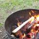 Close-up photo of a metal fire ring with burning wood and cooking—useful detail of campsite amenities (fire pit). Image appears on the campground’s gallery pages on the site.
