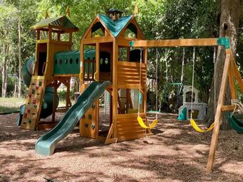 Children’s wooden playground structure set among trees—demonstrates family-friendly on-site recreation shown on the park homepage.