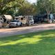 Row of RVs parked at shaded full‑service sites with picnic tables—clear view of typical RV pitches and site layout from the property gallery images.