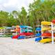 Colorful stacked kayaks/canoes on racks beside natural vegetation — depicts on-site water activity equipment/storage shown in the community gallery.